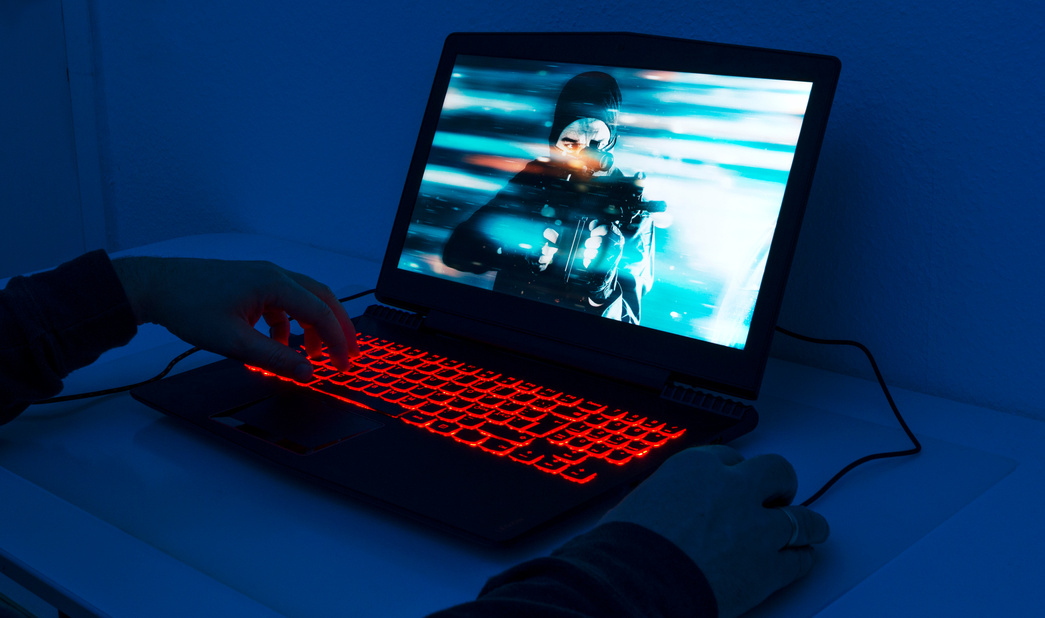 Close up of man playing on gaming laptop at night